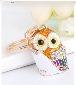 Close-up of golden owl keychain with colorful enamel patterns and sparkling rhinestones