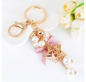 Detail of pink silk bow, white pearls, and golden star on a stylish metal keychain