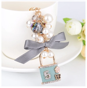 Porte-clés élégant avec perles blanches, nœud gris et pendentif cadenas vert