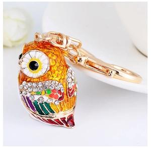 Close-up of owl keychain with colorful enamel and sparkling rhinestones on gold metal