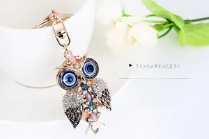 Detail of owl keychain with rose gold metal and multi-color rhinestones on porcelain cup