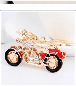 Détail macro du porte-clés moto doré orné de strass blancs et de finitions en émail rouge