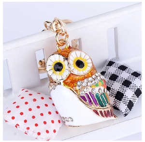 Detail of colorful enamel owl keychain with sparkling rhinestones on a mini bench
