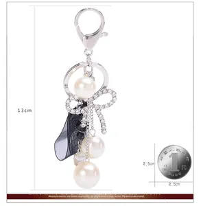 Detailed scale view of elegant bow pearl keychain with ribbon and silver metal hook