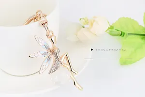 Detailed angel keychain with golden metal wings and crystal ball hanging on a ceramic cup