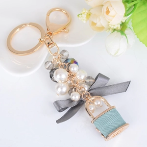 Porte-clés de mode avec anneau doré, perles blanches, nœud gris et pendentif sac bleu