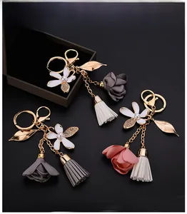 Detailed close-up of floral keychain with gold leaf, fabric rose and soft leather tassels