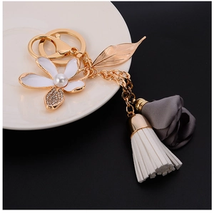 Detail of floral keychain featuring a pearl flower, gold leaf, and chiffon rose pendant