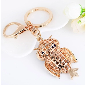 Close-up of golden owl keychain with hollow design, blue eyes and lobster clasp detail