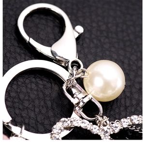 Detailed view of silver lobster clasp and pearl accent on a leather keychain
