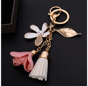 Detail of floral keychain featuring enamel flower, fabric rose, and cream tassel