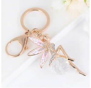 Macro shot of gold angel fairy keychain with pink wings and faceted crystal ball detail