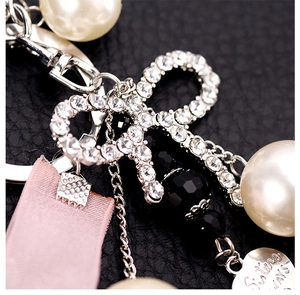 Detail of ribbon keychain with pearl, crystal bow and Sisters Always heart charm