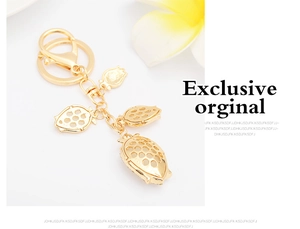 Detail of gold strawberry keychain with three hollow pendants and spring buckle closure