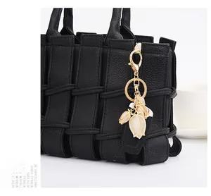 Detail of tulip keychain with white petals and tiny rhinestones on a black bag
