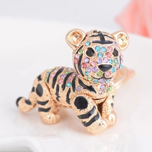 Golden tiger keychain with colorful crystals and black enamel details on a white surface
