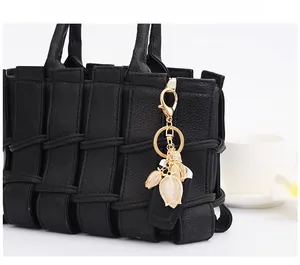 Detail of tulip pendant with opal petals and rhinestones on a black woven leather bag