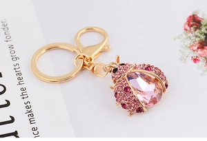 Detailed macro of pink crystal ladybug keychain with rose rhinestones on gold alloy