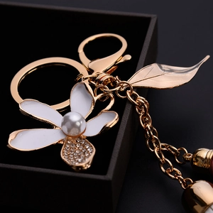 Elegant floral keychain with white enamel petals, gold leaf and white pearl charm