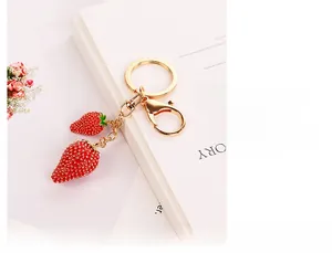 Dettaglio dei ciondoli a fragola rossa con placcatura in oro e motivi a foglie su portachiavi