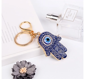 Dettaglio portachiavi mano di Hamsa con occhio blu e cristalli su un libro bianco