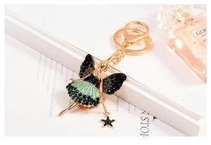 Detailed close-up of a golden ballerina keychain with green rhinestones and star charm