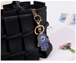 Dettaglio del portachiavi Mano di Fatima e Occhio di Allah su borsa in pelle nera
