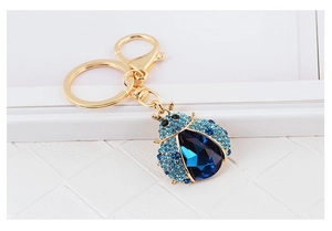 Macro shot of blue gemstone ladybug keychain with gold plating and sparkling rhinestones