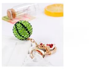 Detail of crystal paved green sphere keychain with enamel watermelon charms and gold clasp