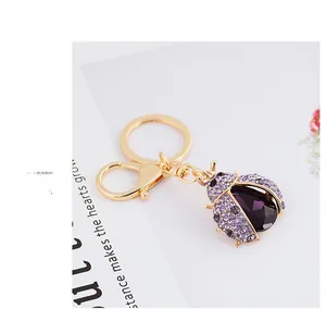 Detailed view of luxury purple ladybug keychain with crystals on a fashion magazine