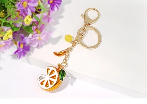 Detail of lemon keychain with gold metal chain, crystals, and green enamel leaves