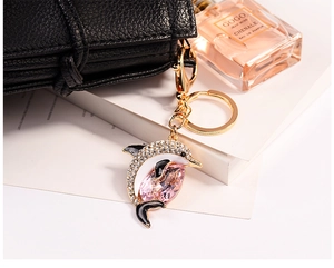 Detailed close-up of a luxury dolphin keychain with pink crystal and diamond-encrusted finish