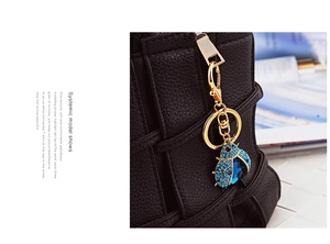 Close-up of blue rhinestone ladybug keychain decoration on a black leather handbag