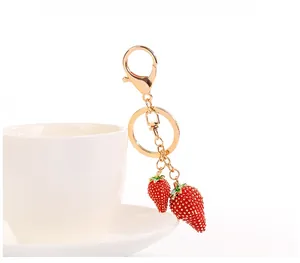 Dettaglio del portachiavi a fragola rossa appeso a una tazza in ceramica bianca