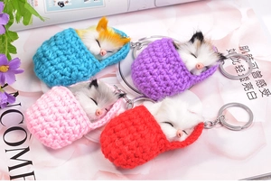Detail view of four colorful sleeping cat plush keychains with crochet sleeping bags