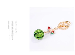 Detailed shot of sparkling rhinestone ball and watermelon enamel charms on gold keychain