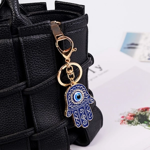 Ciondolo Mano di Fatima con malocchio blu e cristalli su borsa intrecciata