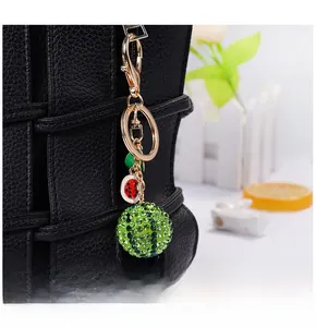 Close-up of sparkling watermelon rhinestone keychain with metal clip on a leather handbag