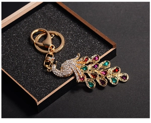 Detailed macro shot of peacock keychain with multicolored crystals on golden alloy