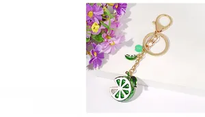 Detail view of a green lemon keychain with rhinestones and tassel on a white stand