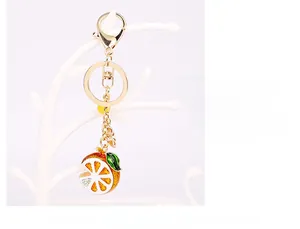 Detailed view of a citrus slice keychain with orange enamel and gold-tone lobster clasp
