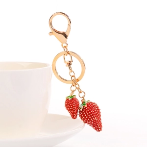 Portachiavi creativo con due fragole rosse e finiture dorate su una tazza in ceramica bianca