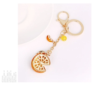 Detail view of a sparkling orange slice keychain with golden alloy edges and beads