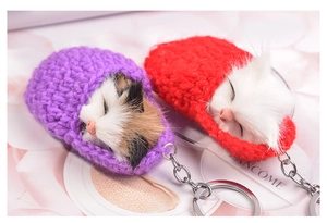 Detailed close-up of handmade knitted sleeping cat keychain with purple and red yarn