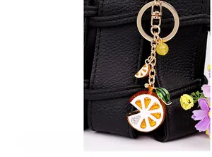 Close-up of golden lemon slice keychain with enamel inlay on a black leather bag
