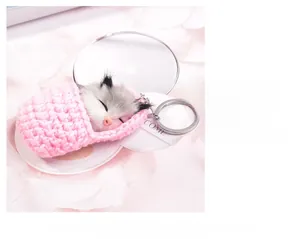 Close-up of fluffy sleeping mouse keychain inside a pink knit pouch with silver chain