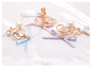Detailed view of pink, blue, and grey satin bow keychains with pearls and star charms