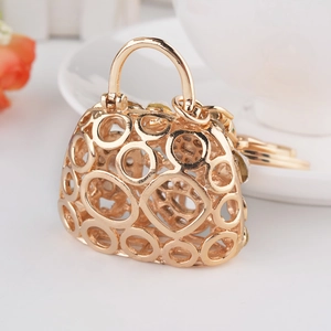 Golden luxury handbag keychain with rhinestone hollow design on white background