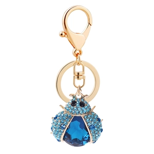 Sparkling ladybug keychain with blue rhinestones and gold plating on white background