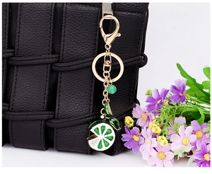 Detailed view of a gold lemon keychain with rhinestones attached to a black woven bag